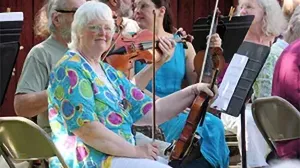 Woman with gray hair posing with a violin. 