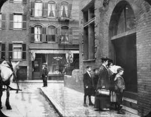 Photograph from 1910, a mother and her children approach the entrance to the dispensary to receive the care otherwise unavailable to them. 