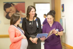 OBGYN physician and clinical professionals talking in hallway. 