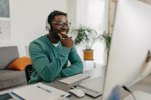 Consumer wearing headphones and taking notes is reviewing cost estimates for healthcare online and happy with the news.